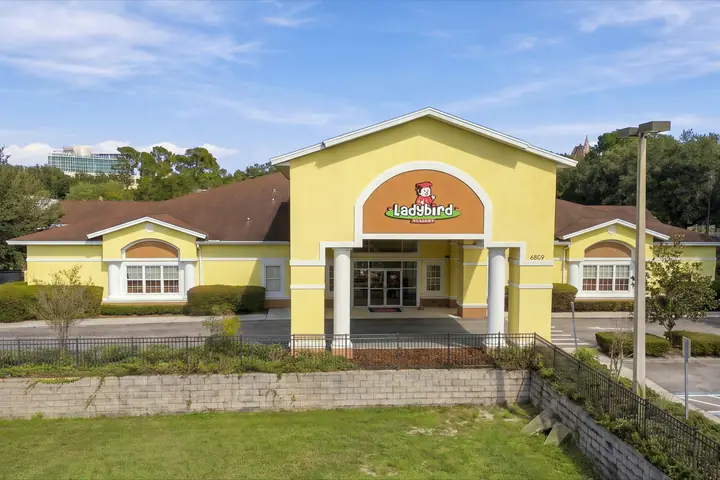 Front entrance of Ladybird Academy of Dr. Phillips, a yellow building with the Ladybird sign