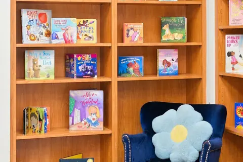 Bookshelves of picture books beside a cozy armchair in the reading room