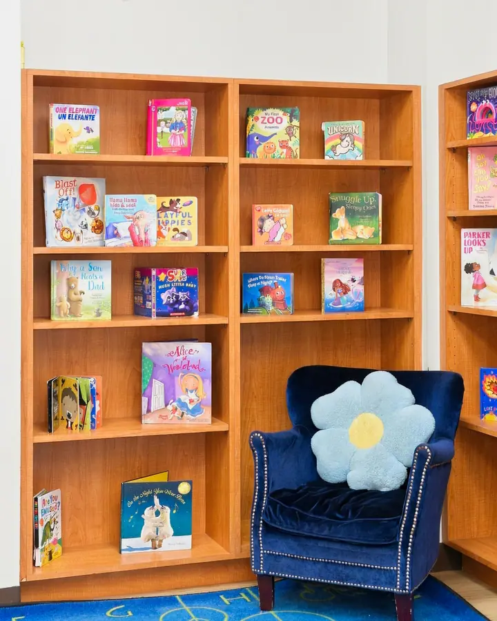 Bookshelves of picture books beside a cozy armchair in the reading room