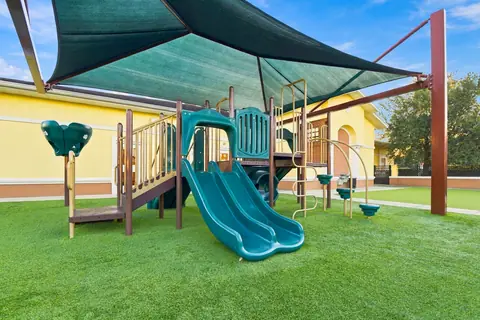 Playground climbing structure and slide under a shade canopy