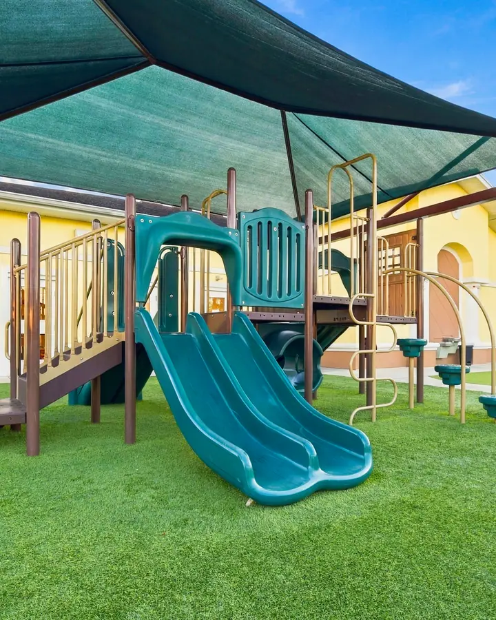 Playground climbing structure and slide under a shade canopy
