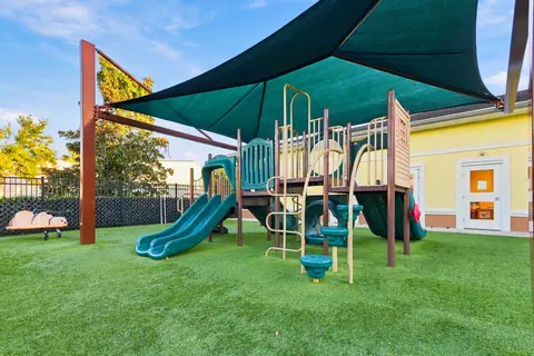 Shaded play structure with slides beside the school building