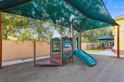 Shaded toddler playground with a small slide