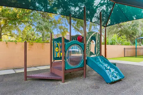 Toddler play structure with a slide under a shade canopy