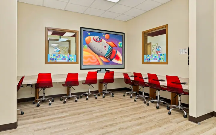Computer lab with red chairs, tablet stations and a rocket ship mural