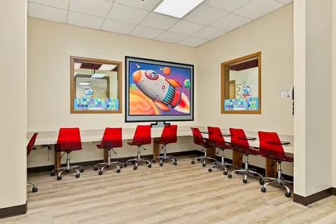 Computer lab with red chairs, tablet stations and a rocket ship mural