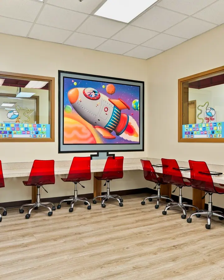 Computer lab with red chairs, tablet stations and a rocket ship mural