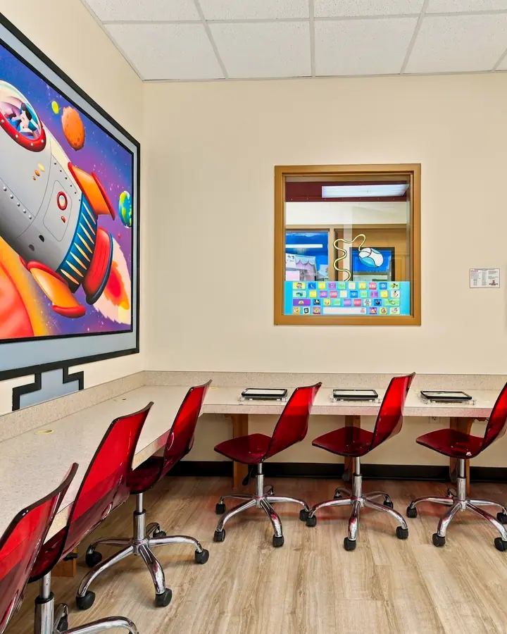 Computer lab with a rocket ship mural and child-height tablet stations