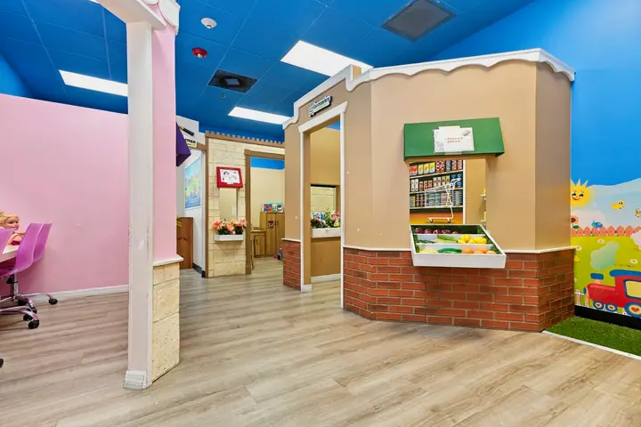 PlayTown street with a pretend grocery stand under a blue sky ceiling