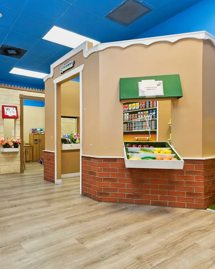 PlayTown street with a pretend grocery stand under a blue sky ceiling