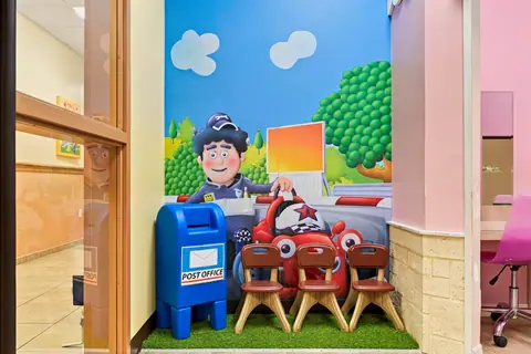 Pretend post office with a mailbox, toy car and child-size chairs