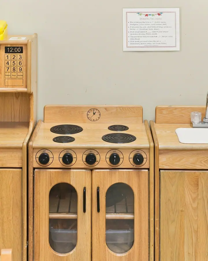 Child-size wooden play kitchen with a stove, oven and sink