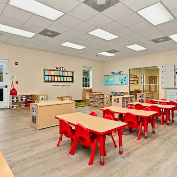 Bright preschool classroom with red tables and chairs