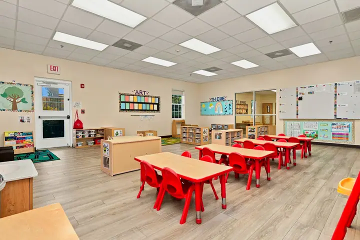 Bright preschool classroom with red tables and chairs