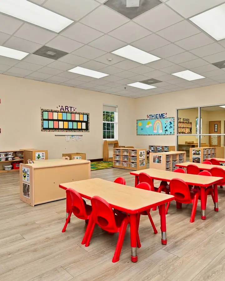 Bright preschool classroom with red tables and chairs