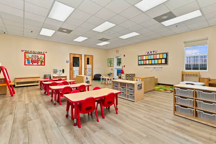 Preschool classroom with red tables, learning centers and art displays