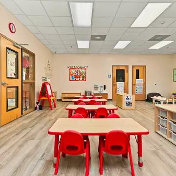 Classroom with red tables, an easel and labeled storage cubbies