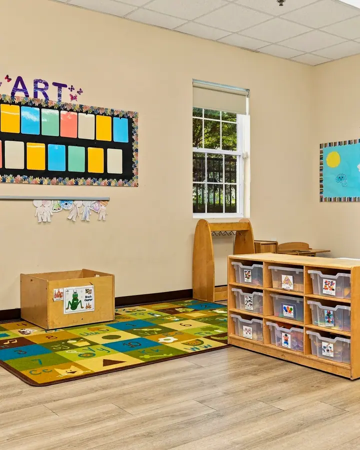Circle-time rug beside the art and theme boards in a classroom