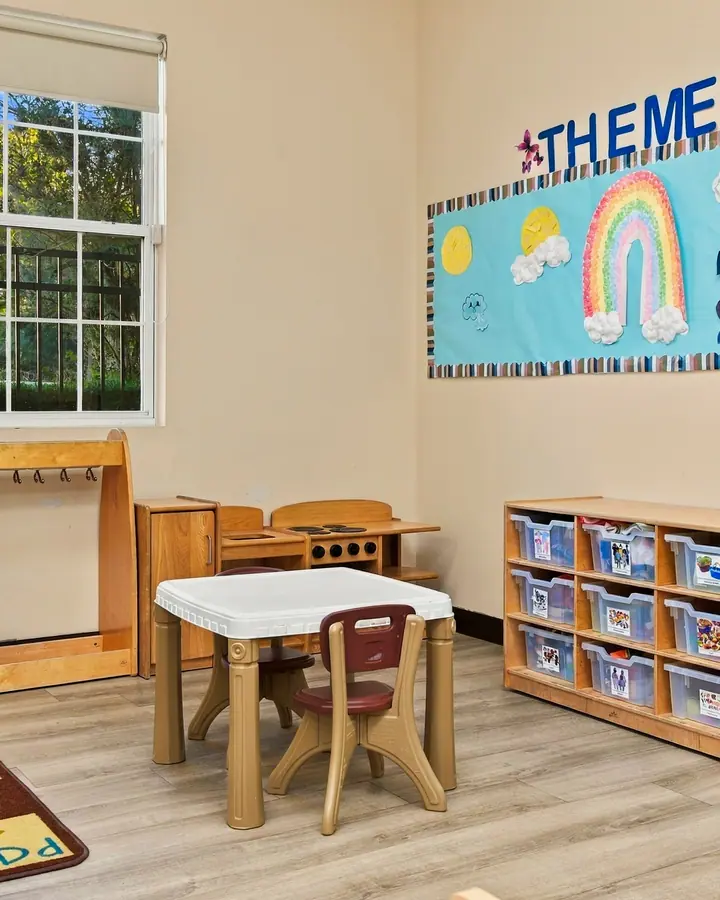 Toddler classroom with a low table, small chairs and a play rug