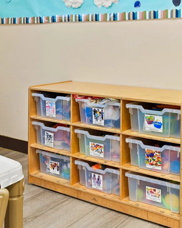 Low shelves of labeled bins in a toddler classroom