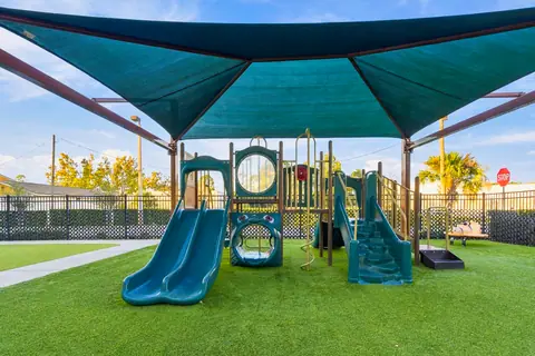 Shaded playground with slides on soft artificial turf