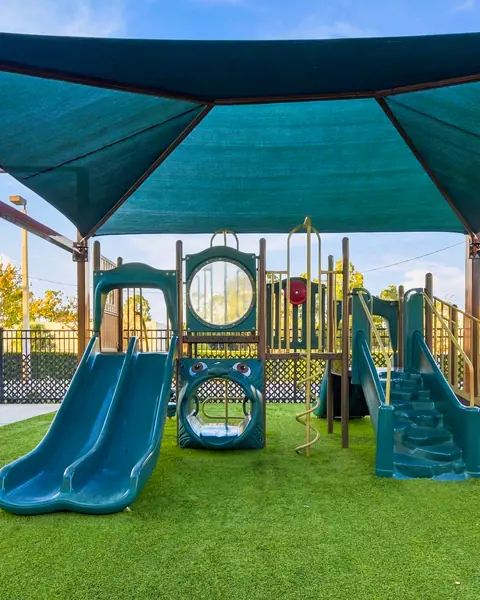 Shaded playground with slides on soft artificial turf
