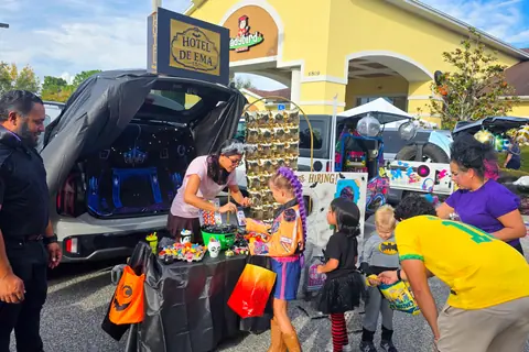 Children in costume collecting candy at a trunk-or-treat car