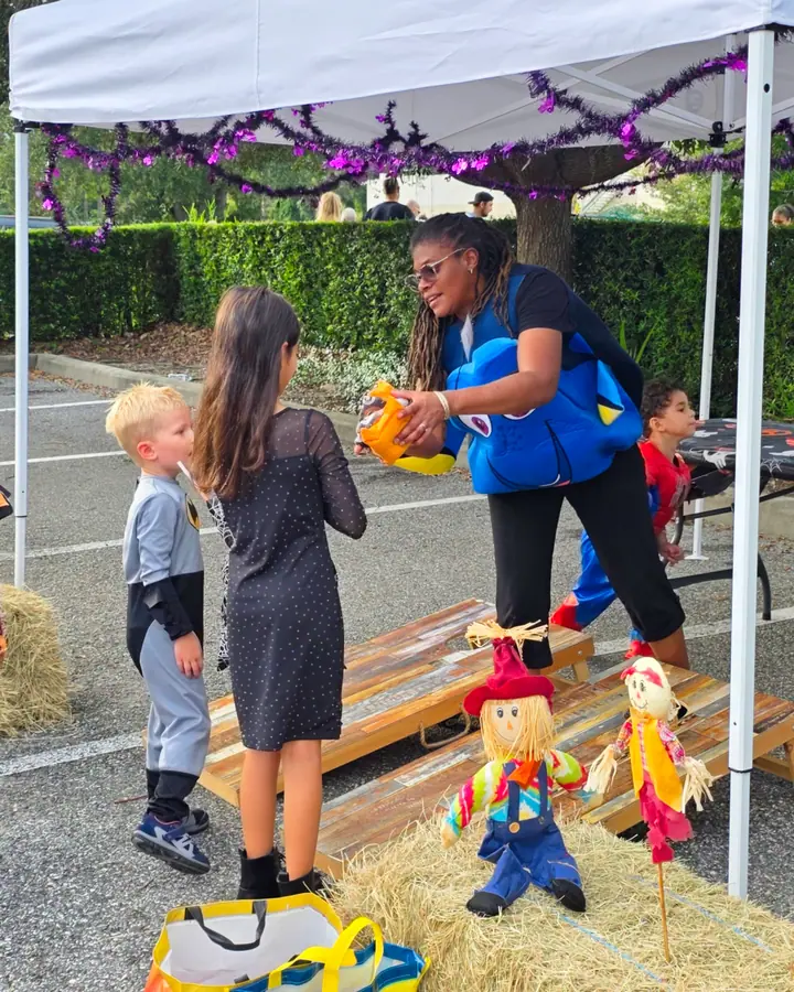 Teacher handing treats to children in costume at the Spooktacular