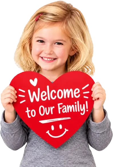 Smiling girl holding a red heart sign that reads Welcome to Our Family!